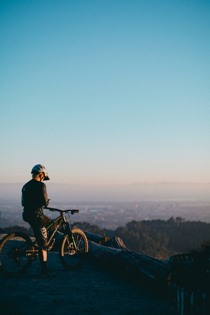man riding on bicycle while standing on peak